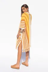 Ruana tejida a rayas horizontales en tonos amarillo, naranja y blanco, con flecos en el borde inferior.