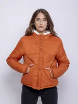 Campera puffer color ladrillo, con capucha forrada en corderito blanco. Tiene cierre frontal con botones a presión y dos bolsillos laterales con cierre.