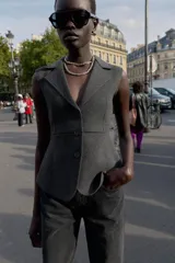 Chaleco entallado de punto color gris oscuro, con cuello solapa, manga sisa y cierre frontal de tres botones.