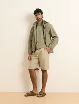 Campera impermeable gris con capucha, cierre frontal y bolsillos laterales con cremallera.