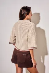 Sweater de tejido abierto de algodón, color beige, con cuello polo, mangas cortas y detalles en color marrón oscuro en los bordes y puños.