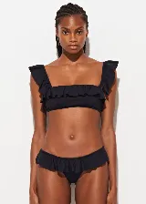 Conjunto de bikini negro con corpiño con escote recto y volados en los breteles y contorno superior, y bombacha clásica con volados en la cintura.