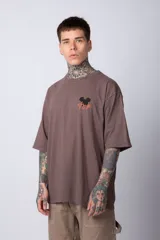 Remera negra de algodón de corte oversize, con mangas cortas y cuello redondo. Estampado pequeño en el frente y diseño grande en la espalda con Mickey Mouse y caracteres orientales en tonos rojizos.