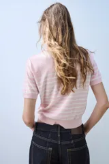 Top de punto de manga corta y cuello redondo, de color rosado con rayas horizontales blancas y aplicación de lentejuelas brillantes en toda la prenda.