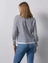 Blusa de gasa estampada con líneas verticales negras sobre fondo beige, de manga larga con puño abotonado. Espalda con abertura y botón.