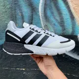 Championes urbanos Adidas modelo ZX 1K Boost, con diseño bicolor en blanco y negro. Presentan una parte superior de malla transpirable con las icónicas tres bandas laterales, refuerzo en el talón y suela con tecnología Boost para mayor amortiguación.