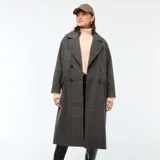 Abrigo largo de mujer, estilo lanoso, con estampado de pata de gallo o príncipe de Gales en tonos grises y marrones. Presenta un corte recto y holgado, cuello con solapas anchas y cierre cruzado con doble botonadura oscura.