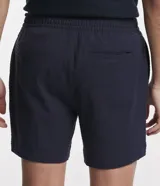 Bermuda de hombre, corte slim, color blanco con textura visible. Confeccionada principalmente en lino y algodón, con un pequeño porcentaje de elastano para mayor ajuste. Presenta cintura elástica y bolsillos laterales.