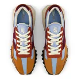 Championes New Balance unisex modelo XC-72, con capellada de gamuza color mostaza, detalles en celeste, bordó y naranja, logo "N" en bordó, entresuela blanca y suela marrón con diseño de tracción agresivo.