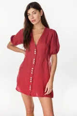 Vestido corto de lino color rojo, con escote en V, cierre frontal con botones claros, mangas cortas abullonadas y cintura entallada con tablas.