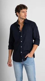 Camisa de manga larga color azul marino con cuello italiano y cierre frontal de botones. Presenta un pequeño logo bordado en el pecho.