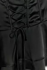 Vestido mini confeccionado en tejido satinado de color negro, con escote recto sin tirantes, detalles de lazos cruzados en el delantero estilo corsé y falda con volantes escalonados.