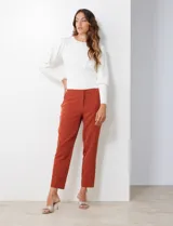 Pantalón de crepe color terracota, de corte recto y largo al tobillo. Presenta detalle fruncido en los bolsillos delanteros y pretina con broche interno y cierre.