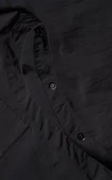 Chaqueta técnica liviana de microfibra con acabado mate, diseño con mangas desmontables que permiten convertirla en chaleco. Cuenta con cuello tipo camisa, cierre frontal oculto, cuatro bolsillos frontales de gran tamaño y puños elásticos. Incluye logo bordado en relieve en el pecho.