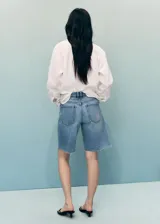 Short de denim tiro medio con diseño de cinco bolsillos, trabillas para cinto y bajo deshilachado.