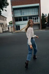 Blusa de escote en pico con volantes frontales, manga larga con puños elásticos y cierre frontal con botones.