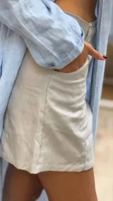 Short de lino en color celeste, con diseño de tiro alto, cierre frontal con botón a la vista y costuras decorativas verticales en el frente.