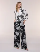 Conjunto de camisa y pantalón amplio con caída fluida. Camisa con escote en V y abotonadura frontal, mangas largas de corte caído con detalle de puntilla calada y puños elastizados fruncidos. Pantalón de tiro alto con cintura elastizada, pierna holgada de corte wide leg con dobladillo ancho en el ruedo y bolsillos laterales.