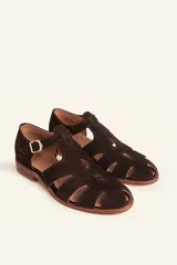 Sandalias de gamuza color marrón, estilo romano con diseño en T, tiras con aberturas laterales y cierre de hebilla metálica en el tobillo. Cuenta con tacón bajo de madera.