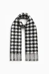 Bufanda larga de poliéster con estampado a cuadros blancos y negros y flecos en los extremos.