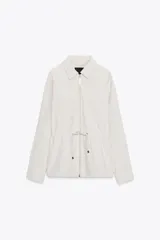 Chaqueta de cuello solapa y manga larga, color blanco roto. Presenta bolsillos delanteros de plastrón con solapa, cintura ajustable con lazada y cierre frontal con cremallera.