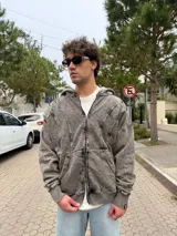 Campera oversize con cierre frontal, confeccionada en tejido con acabado acid wash en tono gris. Presenta costuras curvas decorativas en el frente y puños acanalados.