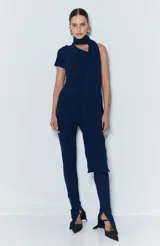 Mono largo negro de punto acanalado, con corte ceñido al cuerpo, un hombro descubierto con manga corta en el lado derecho, diseño de pantalón pitillo con abertura lateral en el bajo y detalle de banda adherida a la pieza.