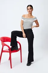 Jean negro de calce flare con cinturón incorporado en la misma tela y silueta ajustada en cadera que se ensancha hacia el ruedo.