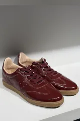Championes de cuero vacuno con acabado brillante tipo charol, color azul marino, con cordones al tono y suela de goma color caramelo.