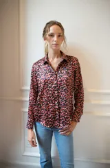 Camisa de corte clásico con cuello camisero y cierre frontal de botones. Confeccionada en seda con estampado animal print en tonos rojizos y negros, presenta mangas largas con puños abotonados y un tablón en la espalda.