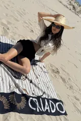 Pareo negro con estampado de rayas verticales blancas y motivos abstractos en tonos marrones.