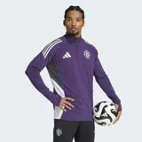 Buzo de entrenamiento Adidas Tiro 25 del Manchester United, color violeta con detalles en blanco. Posee cuello alto con cierre parcial, mangas largas con aberturas para los pulgares y tecnología AEROREADY para el control de la humedad. Presenta el escudo del club y el logo de la marca estampados en el pecho.
