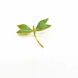 Broche dorado con forma de libélula, decorado con pequeñas zirconias verdes.