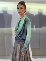 Buzo de doble tejido fino y suave 100% lana merino teñida artesanalmente. Cuenta con una pieza incorporada que permite enroscarla en el cuello a modo de bufanda o chall, dejarla libre hacia el frente o espalda, o enroscarla en el delantero de modo asimétrico. Los puños tienen un ojal para colocar el pulgar y oficiar de semi guantes. Prenda abrigada y confortable ideal para ser usada debajo de un cardigan. Creado y producido en Uruguay.