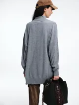 Sweater de tejido de punto color marrón, con cuello alto, corte amplio y tajos laterales en el ruedo. Presenta una costura vertical central en el frente y mangas largas con puños acanalados.