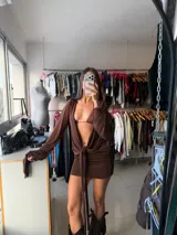 Vestido corto color marrón chocolate, de diseño ajustado con escote profundo y detalle de lazo frontal que se extiende hacia abajo. Posee mangas largas con terminaciones acampanadas.