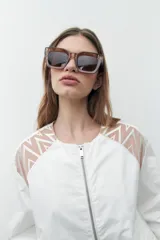 Chaqueta bomber blanca con cierre frontal, mangas largas con diseño geométrico calado en los hombros y puños elásticos.