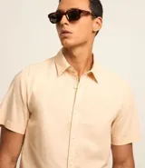 Camisa de manga corta de lino y algodón color beige, de corte confort, con cuello camisero y cierre frontal de botones.