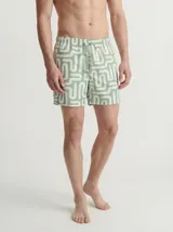Short de baño de color verde con estampado geométrico de líneas blancas, cintura elástica con cordón de ajuste y bolsillos delanteros.