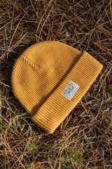 Gorro de lana mostaza con etiqueta bordada de la marca Denali.