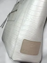 Bolso tipo shopper de cuero natural con textura simil cocodrilo, asas dobles largas para el hombro y bolsillo exterior con cierre en la parte frontal.