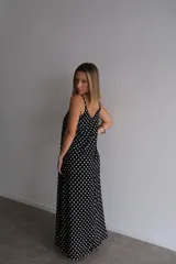 Vestido largo de crepe con estampado de lunares negros sobre fondo blanco. Presenta un diseño de corte holgado con breteles finos y escote redondeado.