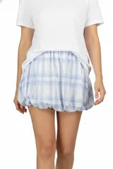 Falda mini de poliéster, color blanco con estampado a cuadros en azul claro. Diseño con elástico en la cintura y en el dobladillo, creando un efecto abullonado.