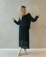 Vestido midi negro de seda italiana, con diseño de capas superpuestas, mangas largas translúcidas y silueta fluida.