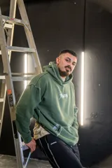 Canguro verde militar con capucha, estampado con texto en el frente y costuras a la vista.