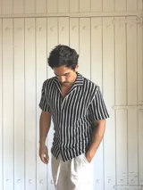 Camisa de hombre tejida a rayas verticales blancas y negras, de manga corta y cuello solapa.