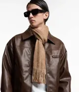 Bufanda beige de punto grueso con efecto melange y flecos en los bordes.