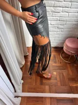 Falda negra de cuero con apliques de cuero color marrón y flecos largos.