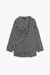 Camisa de manga larga con estampado a cuadros en blanco y negro. Presenta un cuello redondo y un pañuelo multiposición que cae en un drapeado asimétrico sobre el frente.