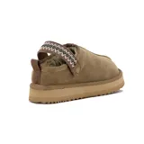 Zapato tipo pantufla de gamuza color kaki, con diseño de plataforma plana y tira ajustable sobre el empeine con detalle de bordado étnico.